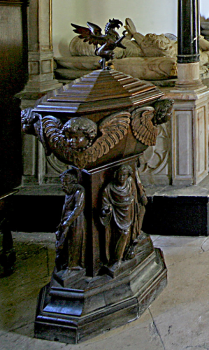 41. 17th century oak font in the chancel, with figures of saints and cherubs heads and a cover  surmounted by the Sandys griffin.